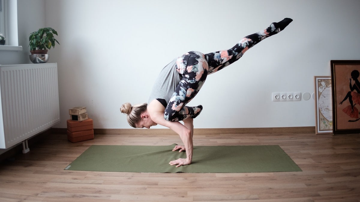a woman doing a handstand on a yoga mat
